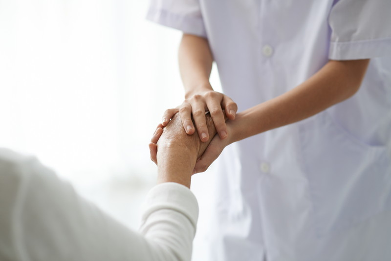 Senior female hand held by compassionate nurse